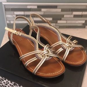 Report gold and platinum flat buckle sandals.